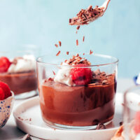 Sprinkling shaved dark chocolate into a jar of pot de creme