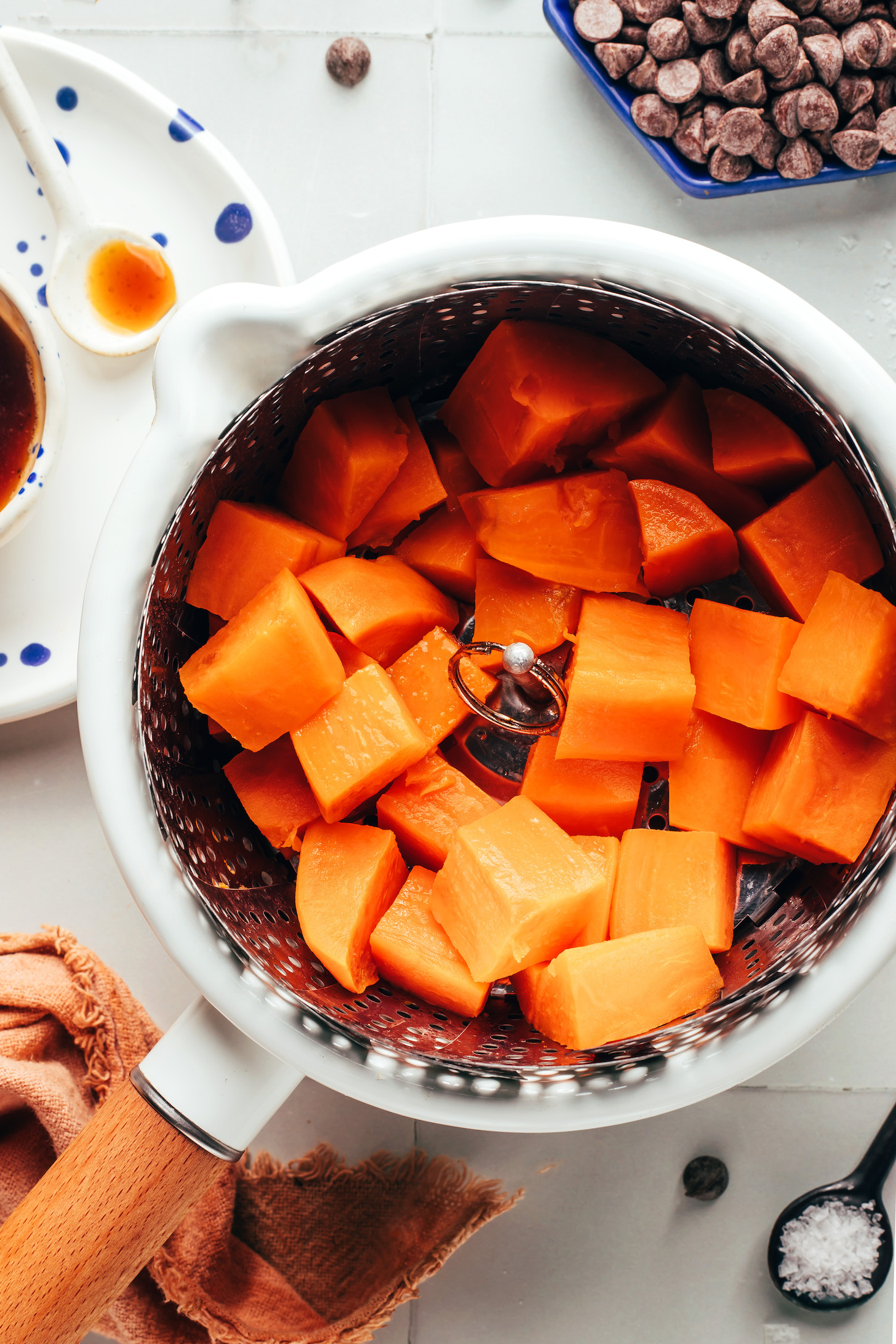 Cubed sweet potatoes in a steamer basket in a saucepan