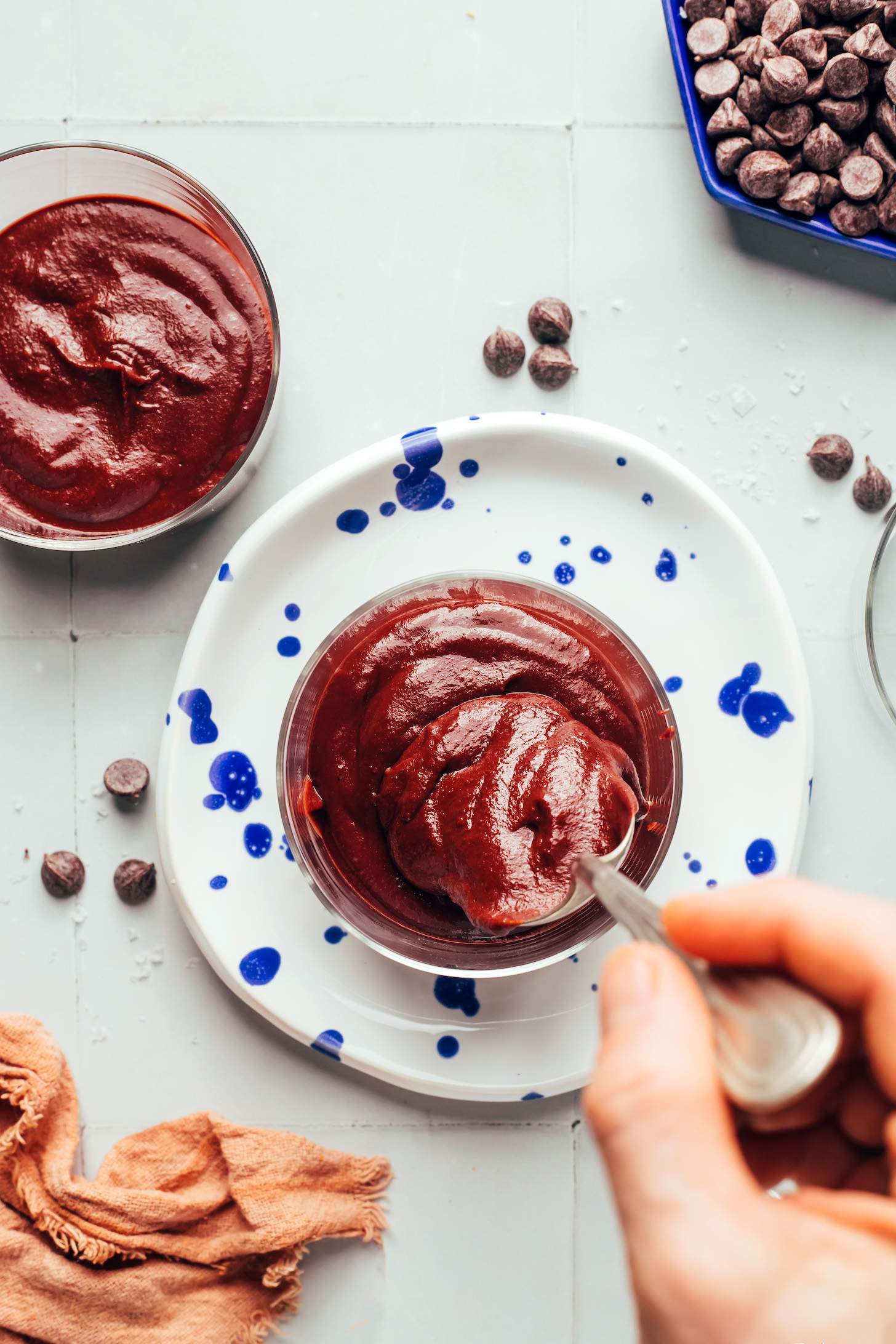 Using a spoon to transfer chocolate sweet potato pot de creme into glasses