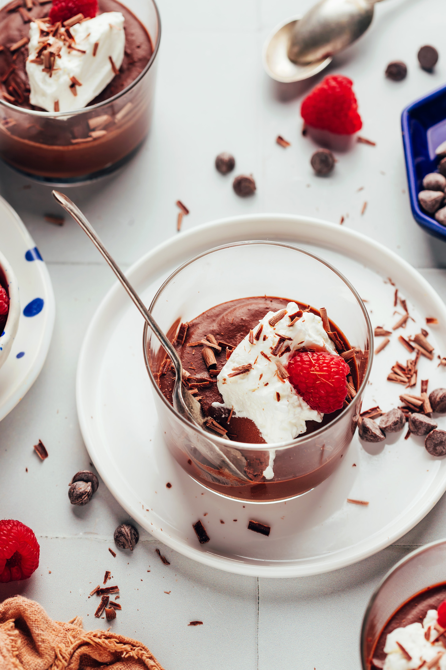 Glasses of chilled dairy-free pot de creme topped with coconut whipped cream and fresh raspberries