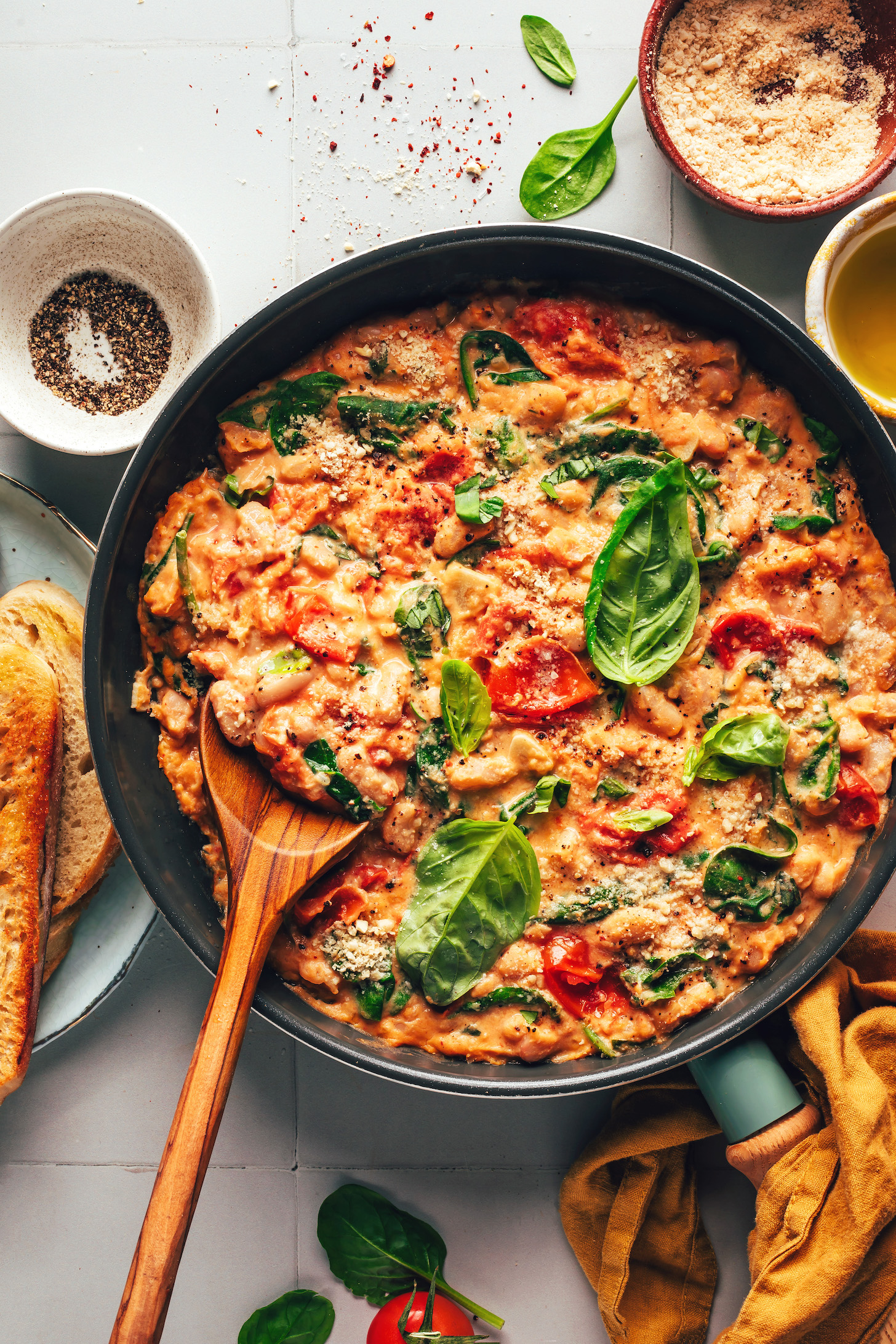 Fresh basil leaves over a pan of our creamy Italian white bean skillet meal