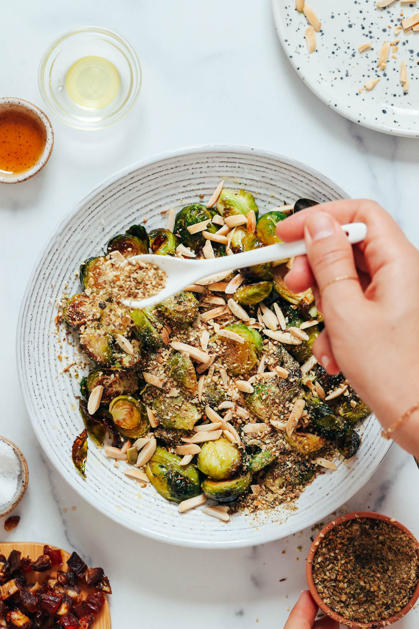 Sprinkling dukkah seasoning over roasted Brussels sprouts