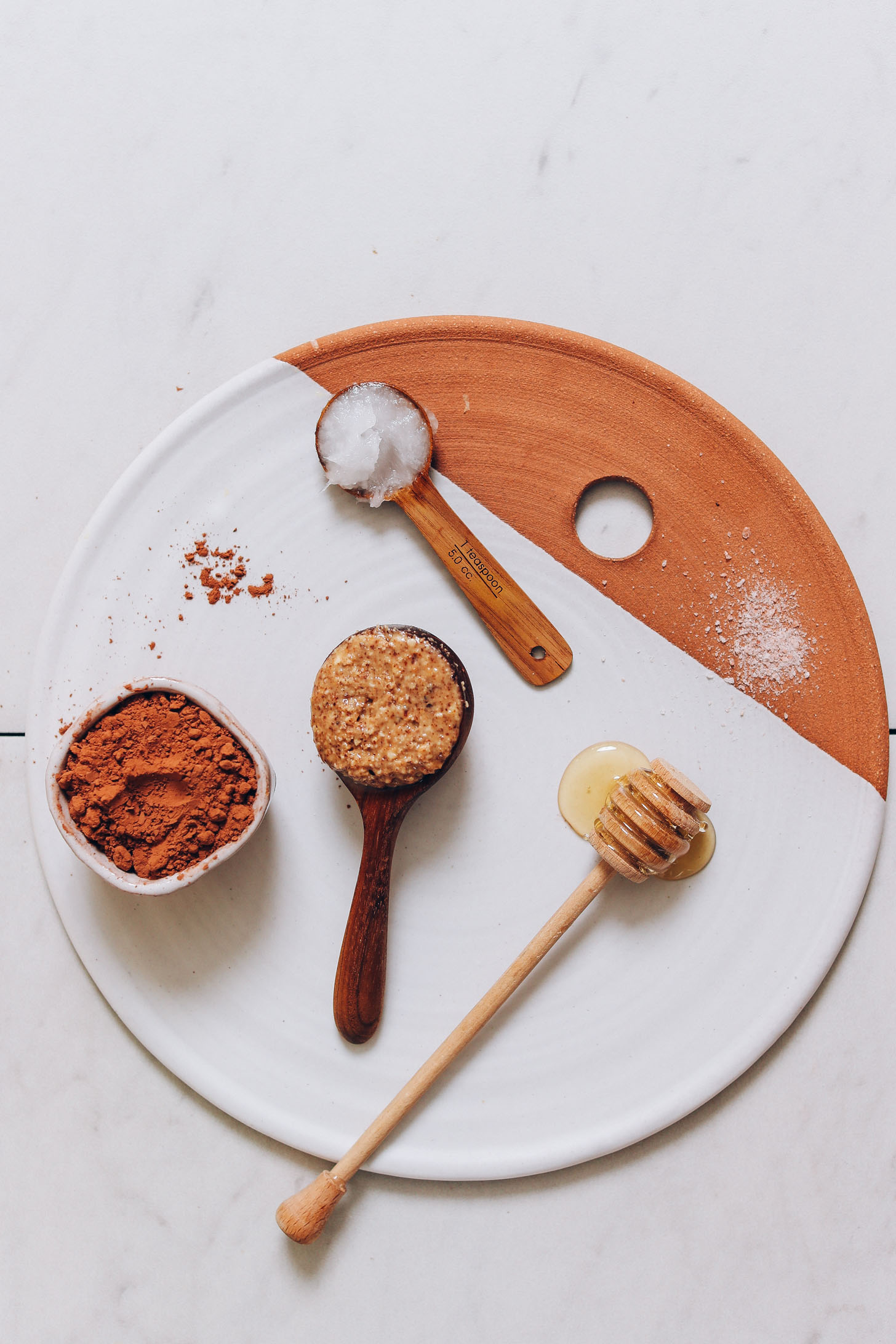 Clay and ceramic tray with honey, almond butter, salt, coconut oil, and cacao powder