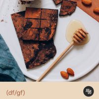 Honey whisk next to dark chocolate bars with cacao powder coating