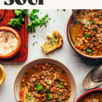Slices of garlic bread in and next to bowls of Italian Lentil Soup also called Zuppa di Lenticchie
